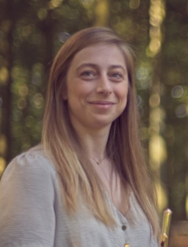a woman holding a trumpet in a forest