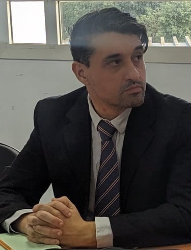Professional businessman in a dark suit and striped tie sitting at a desk during a meeting.