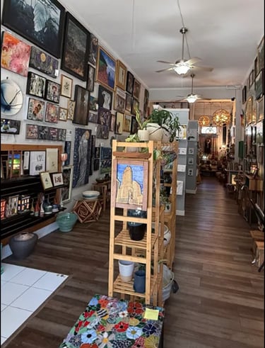 Interior of a local art gallery, The Collective, featuring paintings on walls and handmade pottery o