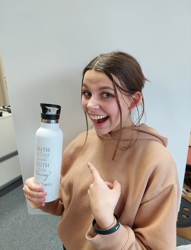 a woman in a brown sweater holding a water bottle