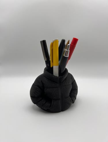 Creative black puffer jacket pen holder for desk organization featuring assorted pens and markers.