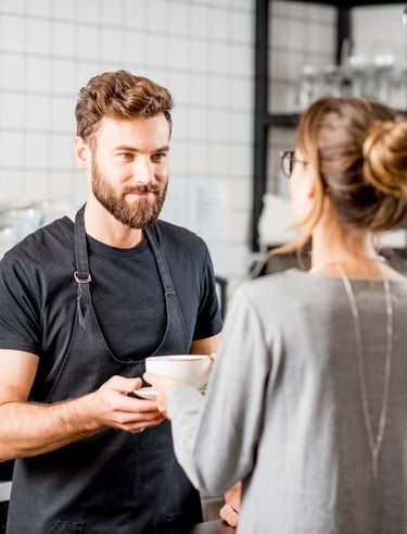 a barista handing coffee to a customer