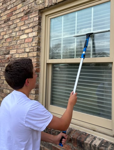 Eddie Sislo is using the squeegee tool to remove streaks from a window.