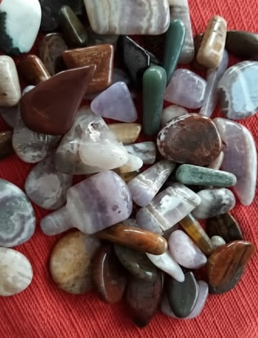 Colección de piedras semipreciosas pulidas y cristales sobre un fondo de tela roja.