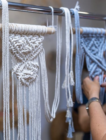 Decoraciones de tapices de macramé hechas a mano siendo elaboradas en un soporte en un taller textil