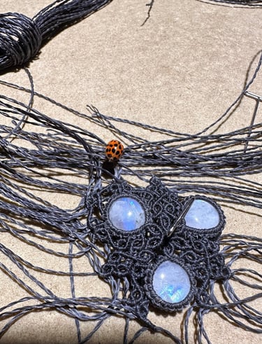 collier en cours d'élaboration, tissage très fin, coccinelle, fil gris Linhasita, peristerites, macramé , artisanat