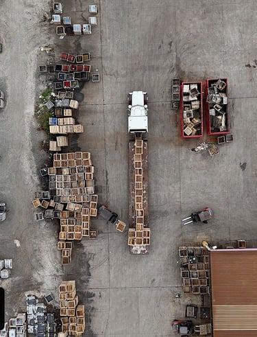 a truck parked in a parking lot getting a shipment loaded by forklifts.