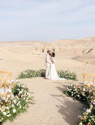a couple standing in a desert with a desert backdrop