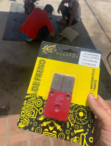 Mano sosteniendo un paquete de pastillas de freno Pacefox para motocicleta