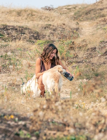 Lifestyle portrait of a woman petting her dog outdoors.