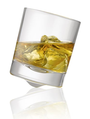 angled glass of whisky on a white reflective background