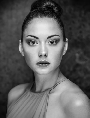 Black and white fine-art portrait of a woman in studio lighting with a neutral expression.