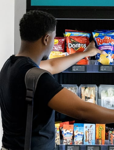a man grabbing snacks from a vending machine