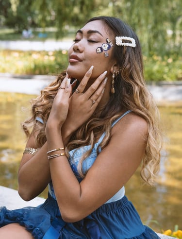 Portrait photo of a young Indonesian woman in a park with flowers and whimsical blue dress