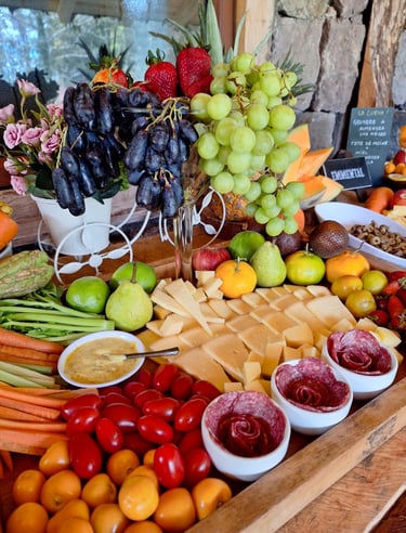 Gourmet charcuterie board with sliced cheese, grapes, strawberries, tomatoes, and salami roses on a wooden tray.