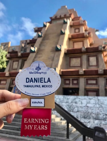 Mano sosteniendo name tag de Disney World frente a la pirámide de México en EPCOT