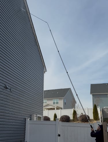 Pressure washing wand cleaning the side of a two-story house.