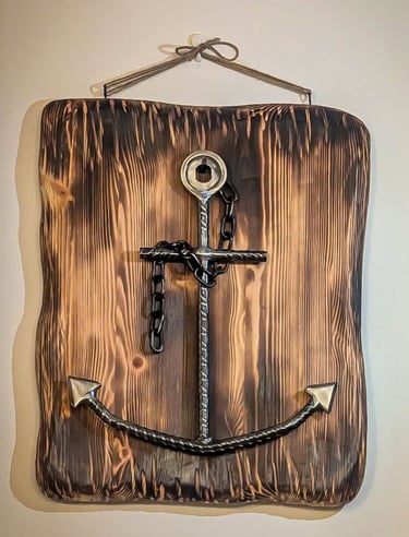 Hanging wall decor featuring a handcrafted metal anchor on a charred wood plaque.