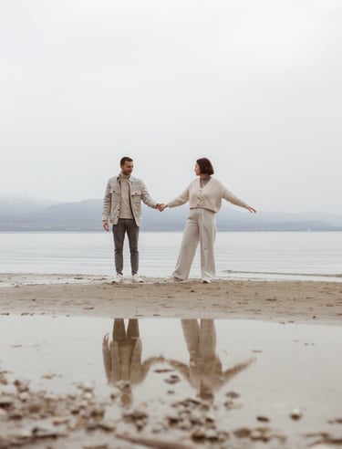 a man and woman holding hands and walking on a beach