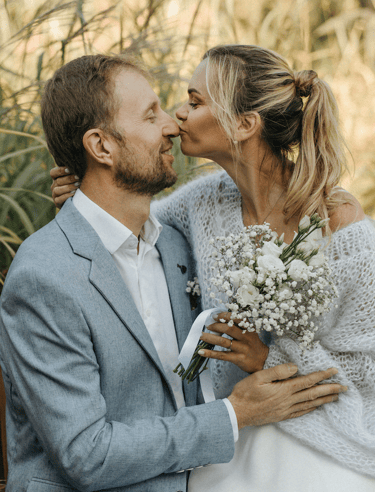 nuotaka bučiuoja vyro nosį ir laiko baltų gėlių puokštę