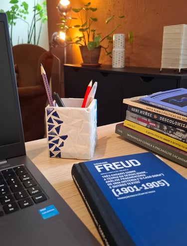 Mesa de trabalho com livros de autoras como Ana Suy, Gayle Rubin e Geni Núñez, ao lado do notebook u