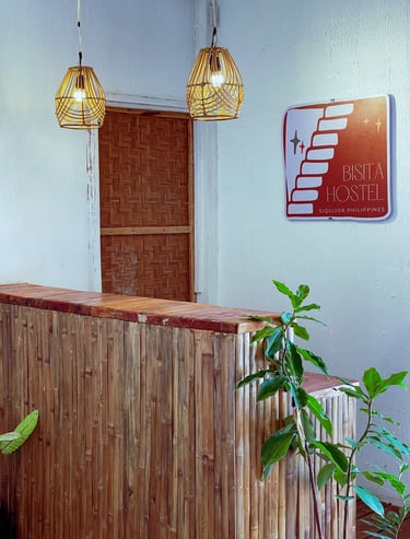 Reception desk of Bisita Hostel in Siquijor Philippines featuring bamboo walls and wicker pendant lights.