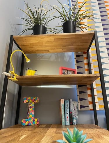 tall storage beside study table with clip on study lamp, accessories and plants