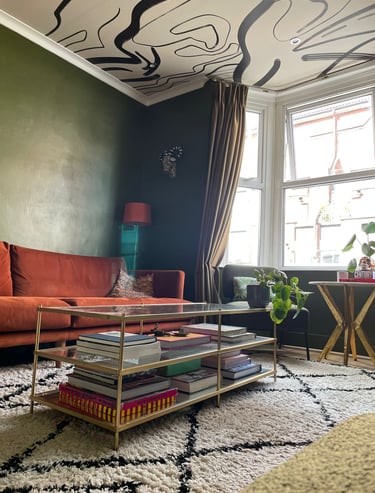 Rust sofa contrasts with deep green walls