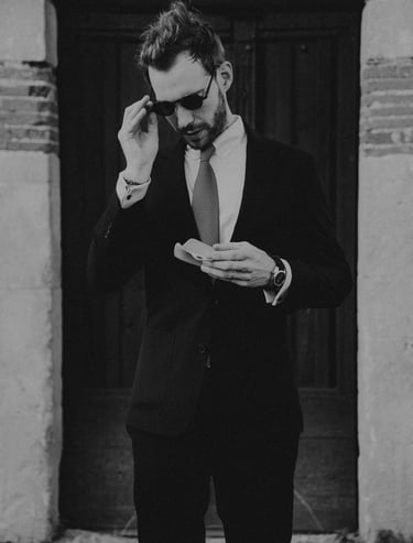a man in a suit and sunglasses is holding a glasses case.