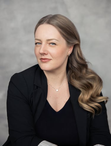 Portrait professionnel d’une femme aux cheveux longs ondulés portant un blazer noir.