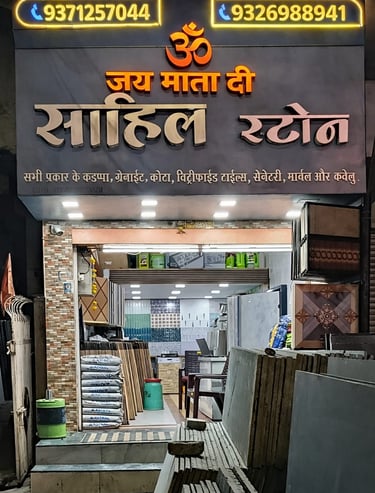 Sahil Stone shop front displaying granite, tiles, and sanitary ware at night with illuminated signage.