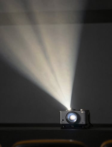 Cinematic photography of a projector beam in a dark theater, dust particles visible in the light, soft off-white light against dark slate grey environment.