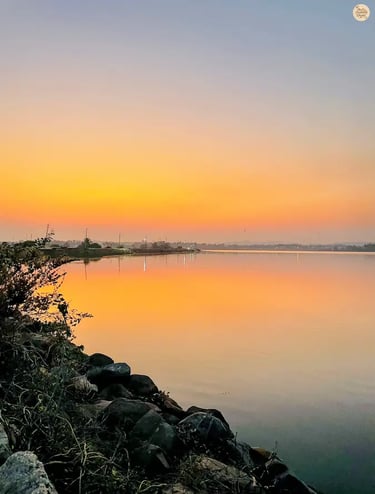 Sunset over Kamalapur Lake in Hampi with pink-hued sky reflecting on the water.