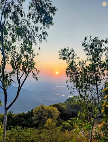 Beautiful sunset at the horizon as seen from Nandi Hills near Bengaluru, casting golden light over misty valleys and hilltops