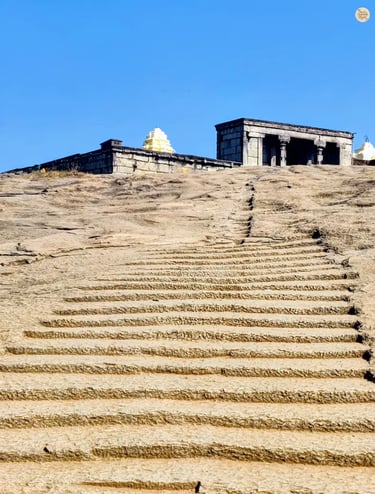 Rock-carved steps leading up to Yoga Nandeeshwara Temple at Nandi Hills, Karnataka, surrounded by greenery and rocky terrain
