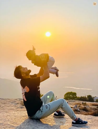 Father and daughter sharing a serene family moment during sunset at Nandi Hills, with golden light over the hills