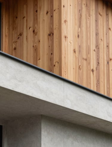 A minimalist architectural detail of a modern Canadian residence. The composition focuses on the clean intersection of warm cedar wood cladding and smooth off-white concrete under soft, diffused daylight.