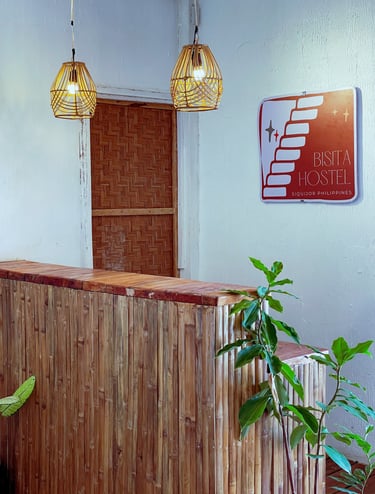 Reception desk of Bisita Hostel in Siquijor Philippines featuring bamboo walls and wicker pendant lights.