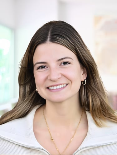 A smiling professional woman with long brown hair wearing a white jacket and gold jewelry.