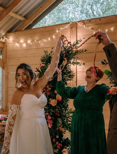 Wedding couple and celebrant smiling and laughing after a handfasting ceremony