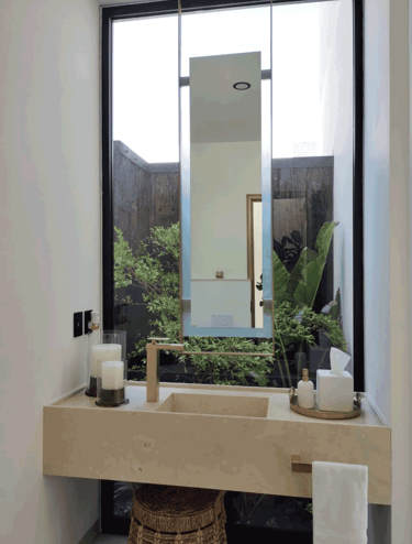 Lavabo minimalista con espejo suspendido y jardín interior | KARÄNA