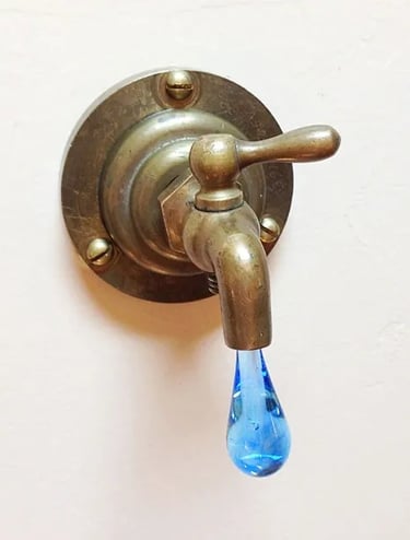 Vintage brass faucet with light blue glass drip coming out ot the spout.