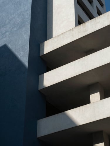 Close-up detail of a modern architectural structure in a Latin American / Hispanic city, focusing on the geometry and shadows, using a palette of deep slate blue and off-white, dramatic professional photography.