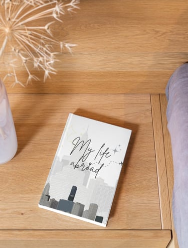 My Life Abroad travel journal on a wooden nightstand next to a dried flower arrangement.