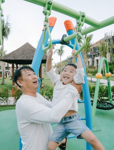Family photography session at The Apurva Kempinski Bali playground area featuring joyful parent and child interaction.