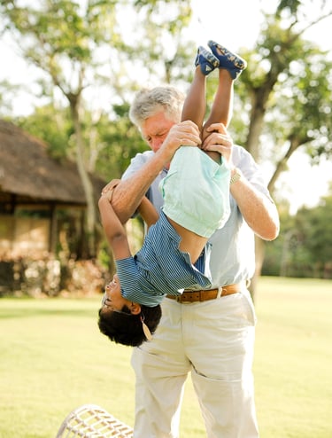 grandfather lifting his grandchild in warm sunset light at rimba by ayana bali during joyful bali family photography