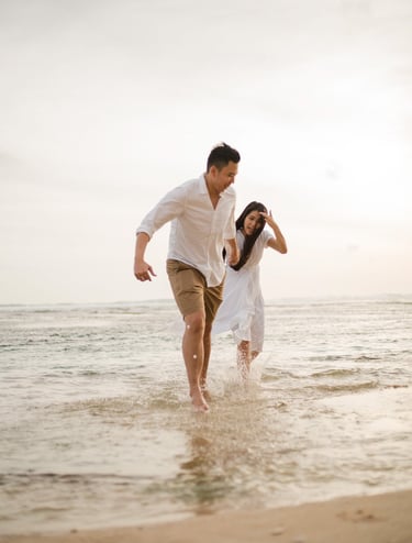 Couple running together in the ocean during proposal photoshoot at Melasti Beach Bali