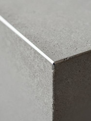 Detail macro photography of polished concrete texture and light silver metal joints. Soft natural light, minimalist and artistic, capturing the tactile quality of high-end materials in a Northern European setting.
