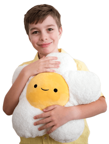 A smiling young boy holding a daisy-shaped plush