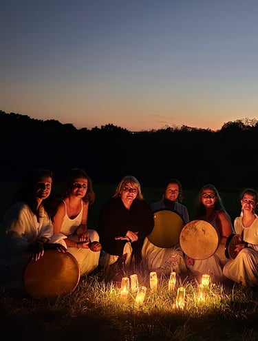 a group of women sitting around a candles at night